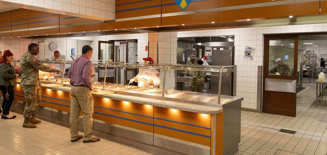 Service members and civilians moving through the serving line of a military dining facility